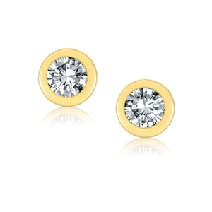 May include: A pair of gold stud earrings with a clear round gemstone in the center of each earring.