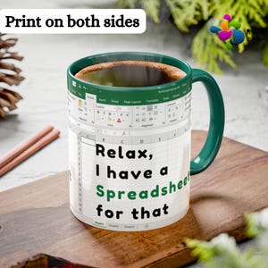 May include: A white ceramic mug with a green handle and rim, filled with coffee. The mug features a spreadsheet design with the text "Relax, I have a Spreadsheet for that." The words "Print on both sides" are at the top.