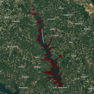May include: Satellite view of Toledo Bend Reservoir, a large body of water surrounded by green forests. Numerous red dots are scattered throughout the reservoir, possibly indicating points of interest or data markers. The text "Toledo Bend" is in the upper left.