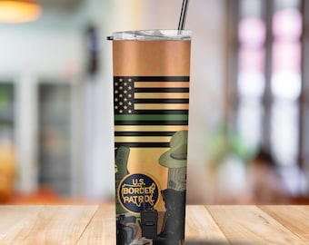 Puede incluir: Un vaso de acero inoxidable con un diseño verde, negro y amarillo. El vaso presenta una bandera estadounidense con una franja verde, un logotipo de la Patrulla Fronteriza de los Estados Unidos y varios equipos de aplicación de la ley.