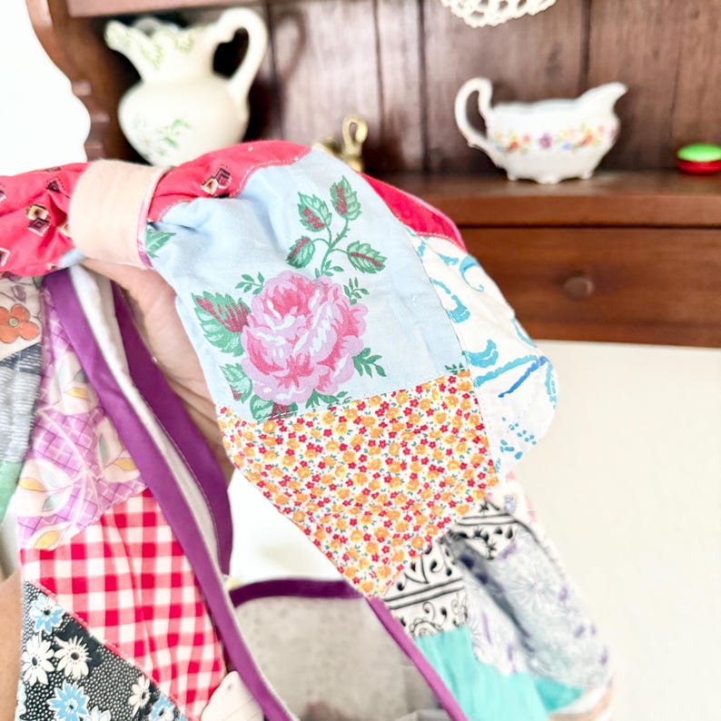 May include: A fabric headband featuring a patchwork design with various patterns including pink roses on a light blue background, red and white gingham, small orange floral prints, and black and white geometric motifs with a solid pink accent.
