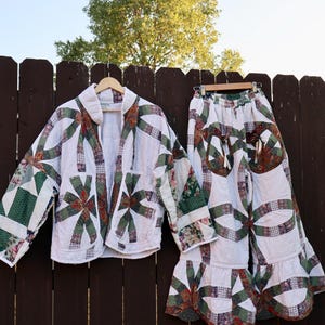 Può includere: Un completo a due pezzi composto da una giacca a maniche lunghe e pantaloni a gamba larga, entrambi realizzati in tessuto trapuntato bianco con un motivo patchwork floreale e geometrico verde, rosso e marrone, con orli a balze sui pantaloni.