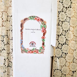 May include: A tall white rectangular cardboard box featuring a decorative label with a floral border. The label text reads American Artists Collection by Kais, Inc. and World Gallery Dolls & Collectibles. The letter G and number 2929 are written in black ink.