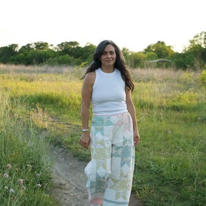 May include: A white sleeveless tank top paired with wide-leg trousers constructed from a quilted fabric featuring a patchwork star pattern in soft pastel shades of pink, green, and yellow, finished with a white waistband and white pointed shoes.
