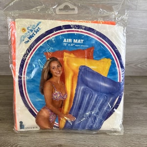 May include: Sealed package containing an Intex Air Mat, 72" x 27" (approximate inflated size). The packaging features a woman in a floral bikini and three inflatable mats in orange, yellow, and blue. The text "The Wet Set" is visible.
