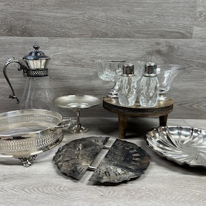 May include: An assortment of vintage silver serving pieces and glassware. Includes a silver-rimmed glass pitcher, a handled serving tray, a small pedestal dish, two salt shakers, and several decorative bowls and platters.