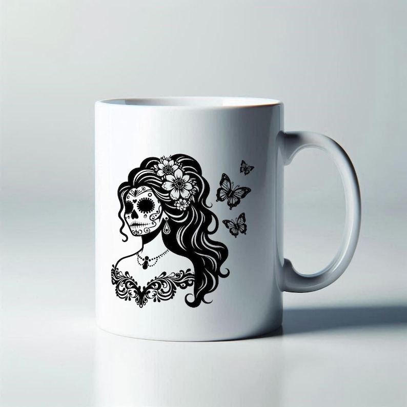 Puede incluir: Taza de cer&aacute;mica blanca con una ilustraci&oacute;n en blanco y negro de una mujer con maquillaje de calavera de az&uacute;car, flores y mariposas. El dise&ntilde;o presenta detalles intrincados y es un art&iacute;culo decorativo.