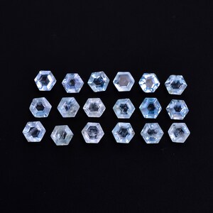 Puede incluir: Una colecci&oacute;n de 16 piedras preciosas de aguamarina facetadas, cada una cortada en forma hexagonal. Las piedras est&aacute;n dispuestas en dos filas de ocho, con las piedras de cada fila alternando en direcci&oacute;n. Las piedras son de color azul claro y tienen una apariencia clara y transparente.