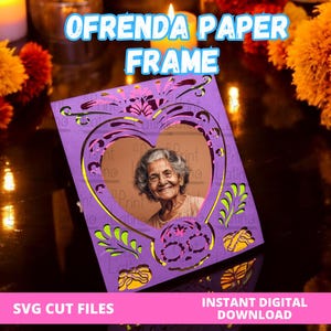 May include: A purple paper frame featuring intricate laser-cut designs, including a central heart-shaped opening displaying a photograph of an older person, decorative floral patterns, and a skull motif at the bottom, with text reading OFRENDA PAPER FRAME.