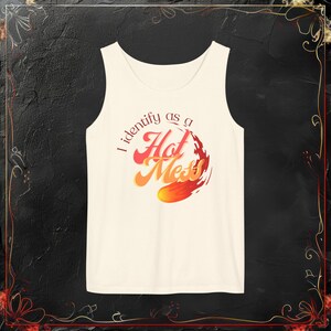 May include: White tank top with a graphic design of a flame with the text "I identify as a Hot Mess" in a retro font.