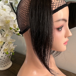 Könnte beinhalten: Schwarze Haarverlängerung mit schwarzer Netzkappe. Die Haarverlängerung ist lang und glatt, und die Kappe ist so konzipiert, dass sie auf dem Kopf getragen werden kann.