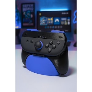 May include: A black and blue video game controller grip. The controller has a black body with blue accents on the top and bottom. The controller features a joystick, buttons, and a directional pad.