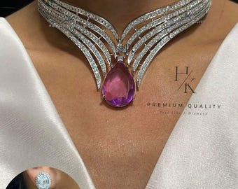 May include: A silver choker necklace with a large, pear-shaped purple gemstone pendant. The necklace is made of multiple rows of small, clear stones. The pendant is surrounded by a halo of smaller stones. The necklace is paired with matching earrings featuring a similar design with a smaller purple gemstone.