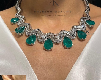 May include: A silver necklace with a wave-like design and emerald green stones. The necklace is paired with matching earrings. The text "PREMIUM QUALITY Feel Like A Diamond" is visible on the image.