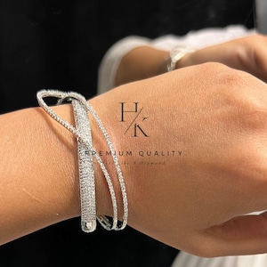 May include: A silver-toned bracelet with a heart-shaped design and encrusted with small, sparkling stones. The bracelet has a delicate, open design with the text "PREMIUM QUALITY Like A Diamond".