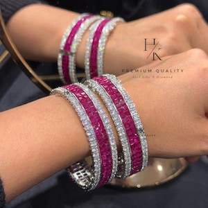 Peut inclure: Bracelets en rubis et diamants. Les bracelets présentent une rangée centrale de rubis carrés, bordée de diamants blancs. Le texte "HK PREMIUM QUALITY Feel like A Diamond" est visible.