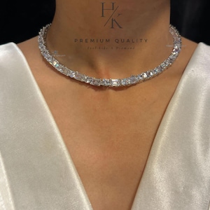 Könnte beinhalten: Eine silberne Choker-Kette mit einer Reihe von klaren, rechteckigen Steinen. Die Kette wird von einem Model getragen, das ein weißes Oberteil trägt. Der Text "PREMIUM QUALITY" und "Feel like a Diamond" ist auf dem Bild zu sehen. Der Text "N-1329" ist in der rechten unteren Ecke des Bildes zu sehen.