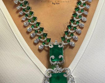 May include: A luxurious necklace featuring emerald-cut green gemstones and sparkling white diamonds. The necklace has a detailed design with a large pendant and smaller stones along the chain. The text "PREMIUM QUALITY" is visible.