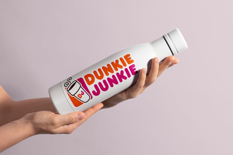 K&ouml;nnte beinhalten: Eine wei&szlig;e Edelstahl-Wasserflasche mit einem pinkfarbenen und orangen Dunkin' Donuts-Logo, auf dem "Dunkie Junkie" steht, und einer stilisierten Kaffeetasse mit den Buchstaben "DJ".