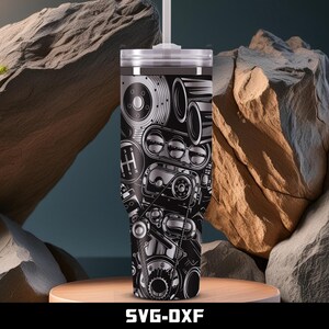 May include: A stainless steel tumbler with a black and silver engine design. The design includes gears, a transmission, and other engine components. The tumbler has a white lid and a straw. The text "SVG-DXF" is at the bottom.