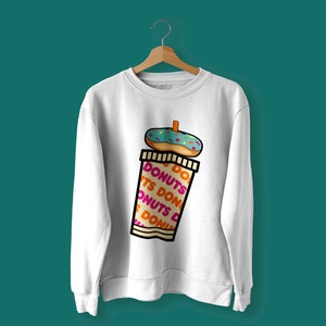 K&ouml;nnte beinhalten: Wei&szlig;er Pullover mit einem Motiv eines Donuts auf einem Kaffebecher mit dem Text "DO DONUTS ITS DONUTS DONUTS DO DONUTS" auf dem Becher.