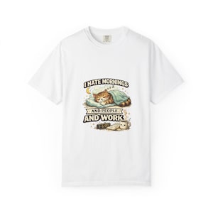 May include: White t-shirt featuring a graphic of a sleeping tabby cat under a blanket. The text reads "I hate mornings... and people... and work." A clock shows 6:00, and a coffee cup is next to a book.