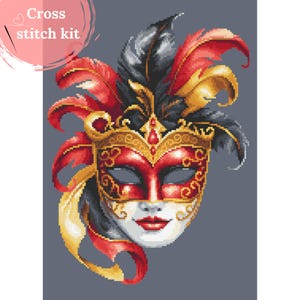 Pode incluir: Kit de ponto cruz com uma máscara veneziana detalhada com detalhes em vermelho, dourado, preto e branco. A máscara tem detalhes dourados ornamentados, penas vermelhas e um rosto branco com lábios vermelhos. O texto "Cross stitch kit" está no canto superior esquerdo.