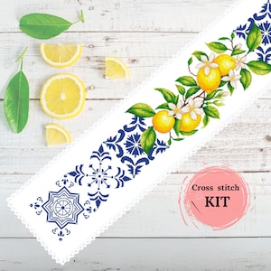 Puede incluir: Un kit de punto de cruz blanco con un diseño de limones, flores y hojas. El diseño está bordeado por un patrón geométrico azul y blanco. El kit incluye el texto "Cross stitch KIT" en un círculo rosa.