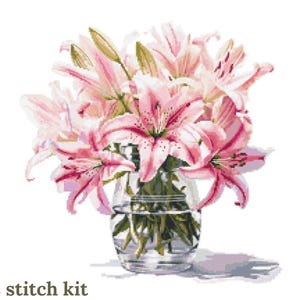 May include: A cross stitch kit depicting a bouquet of pink lilies in a clear glass vase. The lilies are arranged in a loose, natural style, with some of the flowers drooping over the edge of the vase.