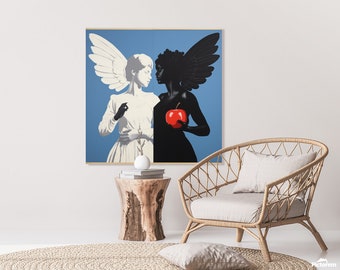 May include: A framed art print depicting two figures with angel wings against a blue background. One figure is in white, the other in black, holding a red apple. The artwork is displayed above a wooden side table and a woven chair.