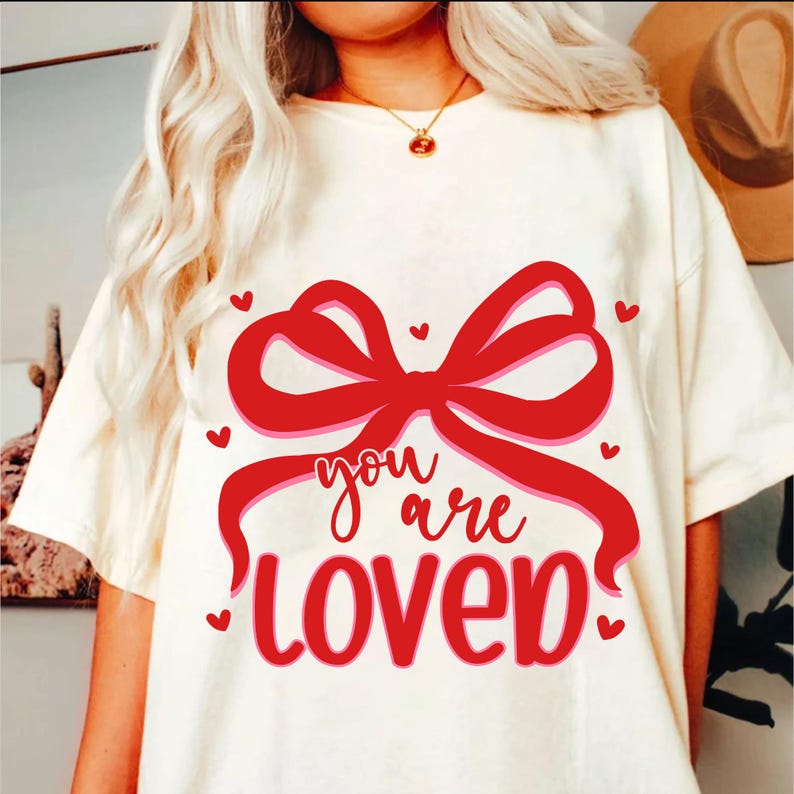 May include: White t-shirt with a red bow and the text "you are loved" in red with a pink outline.