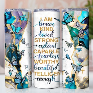 May include: White tumbler with a blue and gold marble design and butterflies. The tumbler has the text "I am brave kind loved strong resilient capable fearless worthy beautiful intelligent enough" printed on it.