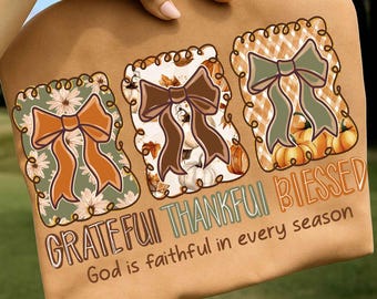 May include: A tan t-shirt with three decorative bow designs. The words "Grateful, Thankful, Blessed" and "God is faithful in every season" are printed below. The bows have autumnal patterns and colours.