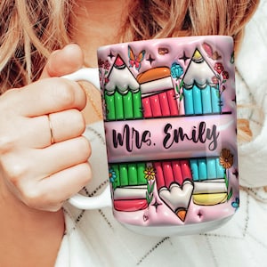 May include: Pink ceramic mug with a colorful design of pencils and flowers. The text "Mrs. Emily" is printed on the mug.