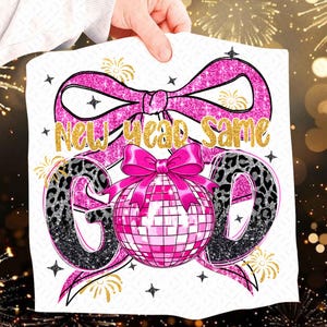 Puede incluir: Gráfico blanco con la frase dorada "New Year Same God". El diseño incluye un lazo rosa, una bola de discoteca y las letras "G" y "D" con estampado de leopardo. Acentos de purpurina dorada y fuegos artificiales completan el tema festivo.