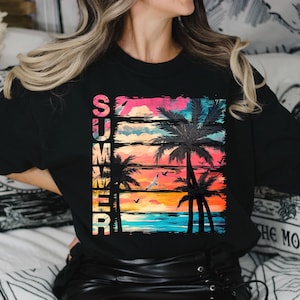 May include: Black long-sleeve shirt with a colorful graphic design. The design features the word "SUMMER" in vertical text, palm trees, birds, and a sunset in shades of pink, orange, and blue.