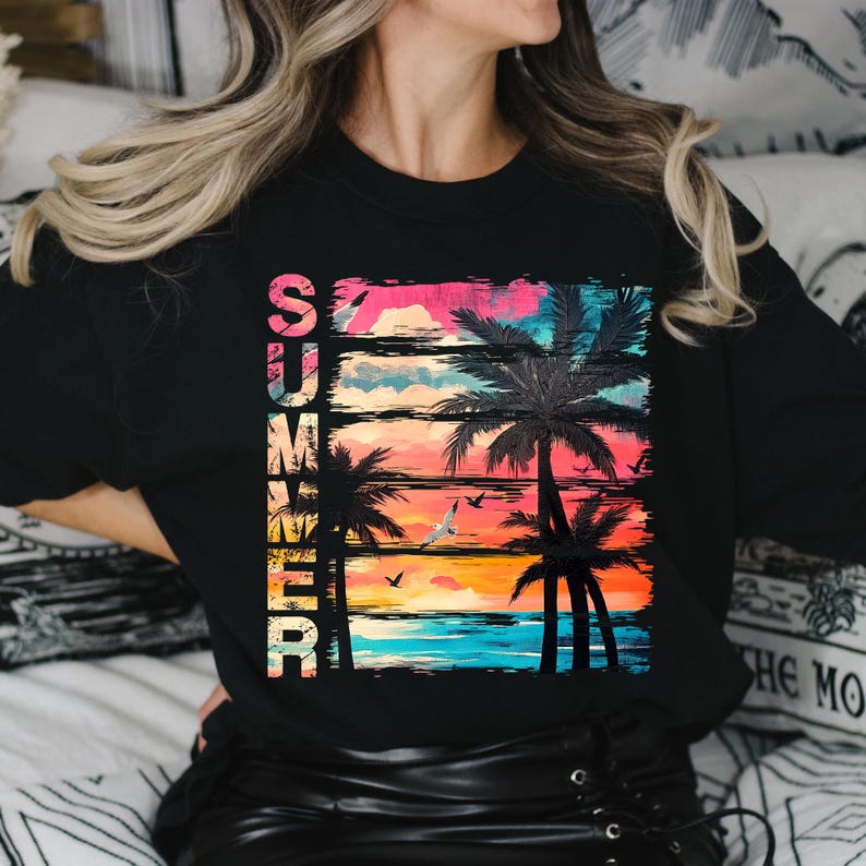 May include: Black long-sleeve shirt with a colorful graphic design. The design features the word "SUMMER" in vertical text, palm trees, birds, and a sunset in shades of pink, orange, and blue.