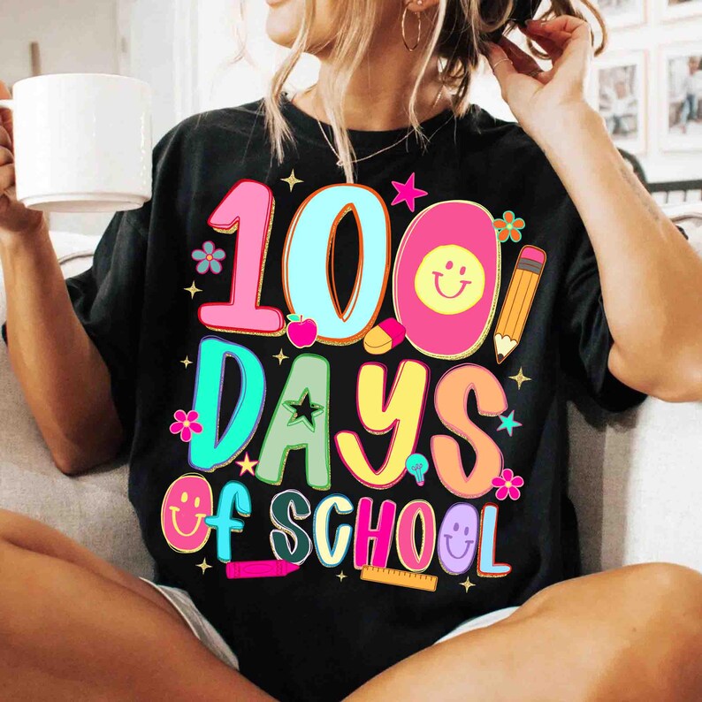May include: Black t-shirt featuring the text "100 Days of School" in a vibrant, multi-coloured design. The graphic includes a smiling egg, a pencil, and other school-related illustrations. The shirt is a casual, everyday wear style.