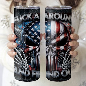 May include: A stainless steel tumbler featuring a skull graphic and the text "F**k Around And Find Out". The skull is decorated with an American flag design.