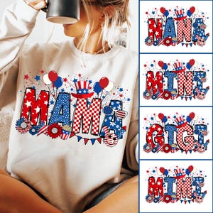 May include: A white sweatshirt with a red, white, and blue graphic design that says "Mama" with fireworks, balloons, and stars. The graphic also includes a red, white, and blue hat with a star on top.