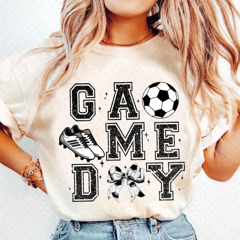 May include: White t-shirt with black glitter text that reads "GAME DAY" with a soccer ball, soccer cleats, and a bow with a soccer ball pattern.