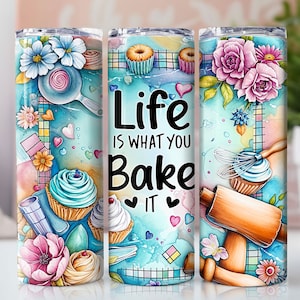 Puede incluir: Un vaso blanco con un diseño colorido que presenta cupcakes, herramientas para hornear y el texto "Life is what you bake it".