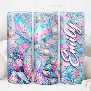 May include: Three stainless steel tumblers featuring a mermaid tail and seashells design. The tumbler on the right has the name "Emily" written on it.