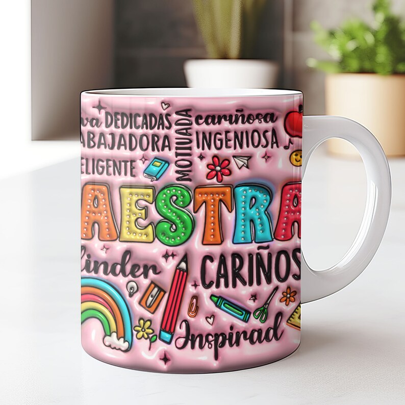 May include: Pink ceramic mug with a colorful design that says "MAESTRA" and includes words like "dedicadas", "cari&ntilde;osa", "motivada", "ingeniosa", "linda", "cari&ntilde;os", and "inspirad".