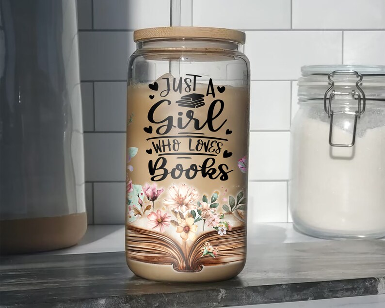 K&ouml;nnte beinhalten: Ein Glasgef&auml;&szlig; mit einem Holzdeckel und einem Blumendesign. Das Gef&auml;&szlig; tr&auml;gt ein Zitat, das lautet "Just a girl who loves books" mit einem Stapel B&uuml;cher und Herzen.