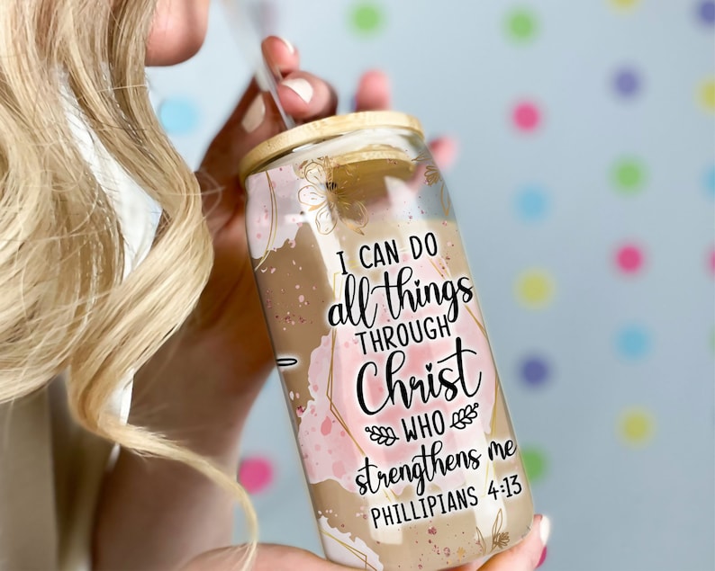 May include: A clear glass tumbler with a wooden lid and a straw. The tumbler has a pink and gold watercolor design with the text "I can do all things through Christ who strengthens me Philippians 4:13".