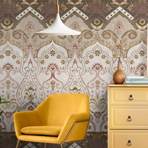 May include: A yellow armchair sits in front of a wall with a brown and white patterned wallpaper. A yellow dresser with black drawer pulls is to the right of the chair. A painting hangs on the wall above the dresser.