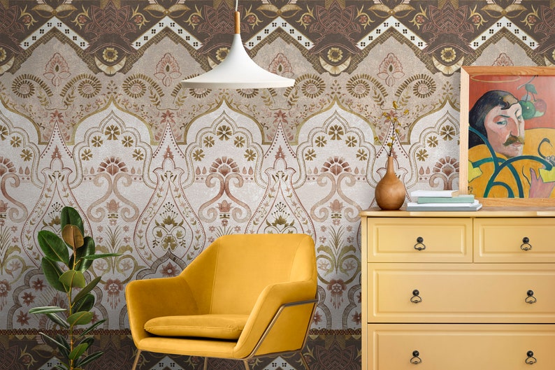 May include: A yellow armchair sits in front of a wall with a brown and white patterned wallpaper. A yellow dresser with black drawer pulls is to the right of the chair. A painting hangs on the wall above the dresser.