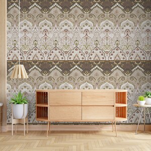 May include: A wooden dresser with four drawers sits in front of a wall with a patterned wallpaper. The wallpaper features a repeating design of brown, beige, and gold arches with intricate details. The dresser has a light wood finish and is accented with a decorative trim.
