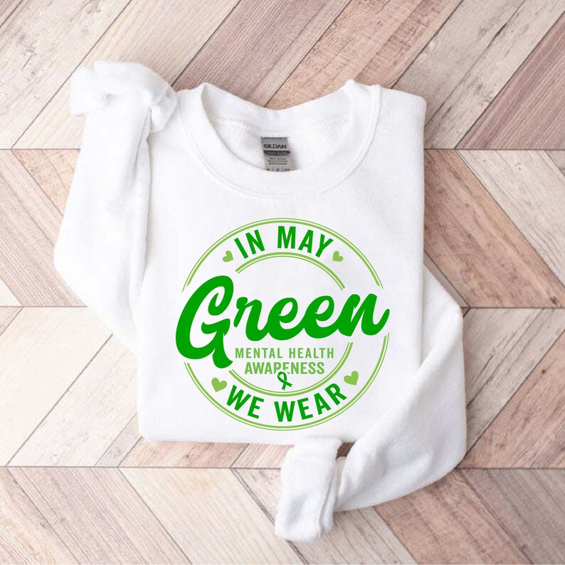 May include: White sweatshirt with a green circle graphic that says "In May We Wear Green" with the text "Mental Health Awareness" inside the circle.